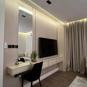 een woonkamer met een televisie en een bureau met een stoel bij نور هوستيل in Riyad