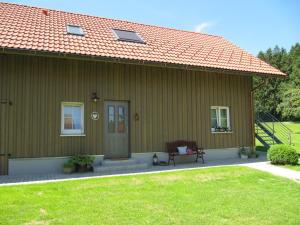 una casa verde con un banco delante en Claudis Ferienhäusle, en Amtzell