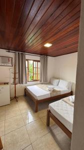 een slaapkamer met twee bedden en een houten plafond bij GO Hotelaria in Búzios