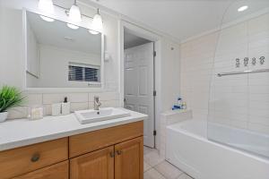un bagno bianco con lavandino, vasca e specchio di Renovated North Vancouver Gem a North Vancouver Altre 49 foto