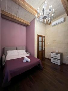 a bedroom with a large bed and a chandelier at De Rohan Central Townhouse 38 in Taʼ l-Infetti