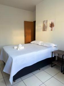 a bedroom with a large white bed with two pillows at Kitnet - Centro - Ipatinga in Ipatinga