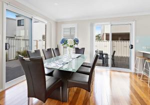 a dining room with a glass table and chairs at Haus on Moore in Oak Flats