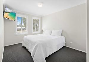 a white bedroom with a bed and two windows at Haus on Moore in Oak Flats +25 photos