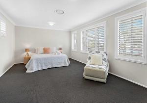 a white bedroom with a bed and a chair at Haus on Moore in Oak Flats