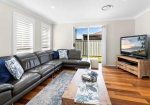 a living room with a leather couch and a flat screen tv at Haus on Moore in Oak Flats