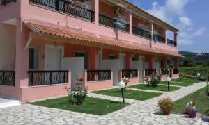 een roze appartementencomplex met een binnenplaats bij Ferienhaus Elena in Agios Georgios