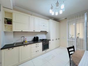 a kitchen with white cabinets and a sink and a table at Apartament new in Chişinău