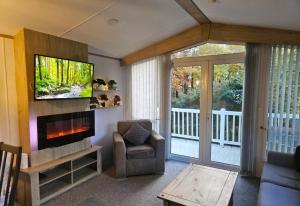 ein Wohnzimmer mit einem TV, einem Sofa und einem Stuhl in der Unterkunft The Treehouse Northumberland in Swarland