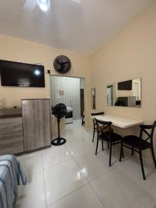ein Wohnzimmer mit Tisch und Stühlen und einem Fernseher in der Unterkunft Kit Jd Guilhermina in Praia Grande