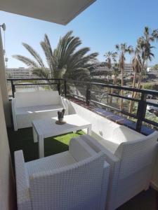 a balcony with white chairs and a table and palm trees at Apartment Club Paraíso in Adeje