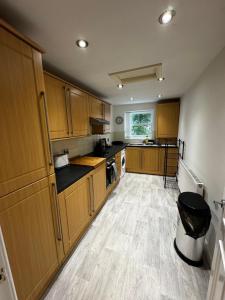 a large kitchen with wooden cabinets and a floor at No 4 AT SANDRINGHAM - LARGE 2 BED NEAR SEFTON PARK in Liverpool