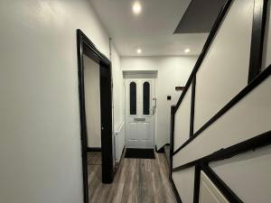 a hallway with a white door and a wooden floor at Rest & Recover in Wednesbury
