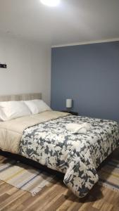 a bedroom with a bed and a blue wall at Hostal Milaris in Calama