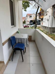 a table and a blue chair on a balcony at Apartman Zaki luxury in Borča
