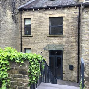 een bakstenen gebouw met een zwarte poort en een deur bij Beautiful 3 bed house in central Hebden Bridge in Hebden Bridge