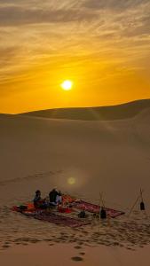 Dos personas sentadas en un bote en el desierto al atardecer en Lumir Surf House, en Tamraght Ouzdar