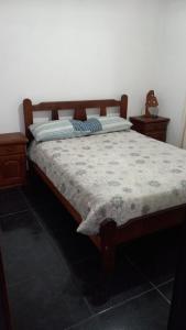 Un dormitorio con una cama grande con marco de madera. en Los Gringuitos - Trapiche, en Trapiche