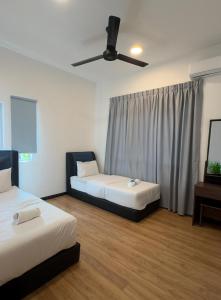 New Homestay Sandakan Rimbayu 12pax في سانداكان: غرفة بها سريرين ومروحة سقف