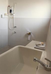 New Homestay Sandakan Rimbayu 12pax في سانداكان: حمام أبيض مع حوض استحمام ودش