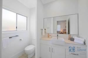 a white bathroom with a sink and a mirror at 24 The Esplanade in Woodgate