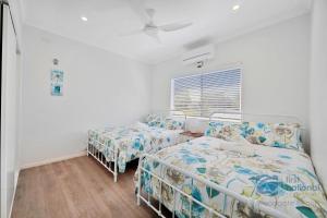 two beds in a room with white walls at 24 The Esplanade in Woodgate