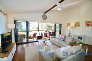 a living room with a couch and a clock on the wall at 58 The Esplanade in Woodgate