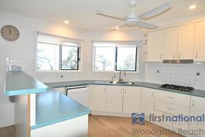 a kitchen with white cabinets and a ceiling fan at 50 The Esplanade in Woodgate