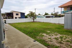 a backyard with a white fence and a grass yard at 50 The Esplanade in Woodgate