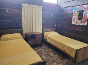 two beds in a room with wooden walls at Cabaña Elun in Panaholma