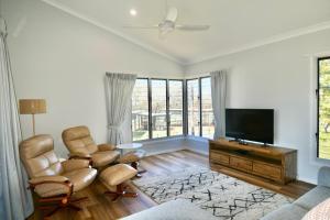 a living room with two chairs and a flat screen tv at 158 The Esplanade in Woodgate +10 photos