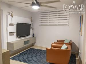 a living room with a tv and a chair at EcoMar Rentals: Villa in Cabo Rojo