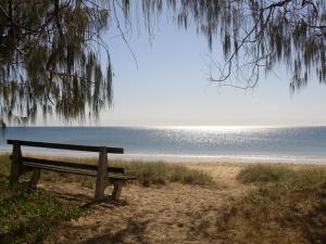 a bench sitting on the beach near the water at 2/84 The Esplanade in Woodgate