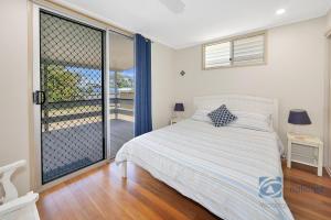 a bedroom with a bed and a sliding glass door at 185 The Esplanade in Woodgate