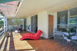 a porch with a red couch and a table and chairs at 185 The Esplanade in Woodgate