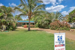 a sign in front of a house with a palm tree at 154 The Esplanade in Woodgate