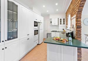 a kitchen with white cabinets and a green counter top at Coastal Palms - Family & Pet-Friendly Beachside Haven in Lake Illawarra
