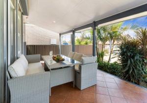 a patio with a table and chairs on a balcony at Coastal Palms - Family & Pet-Friendly Beachside Haven in Lake Illawarra