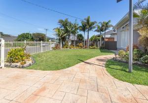 a driveway with a yard in front of a house at Coastal Palms - Family & Pet-Friendly Beachside Haven in Lake Illawarra