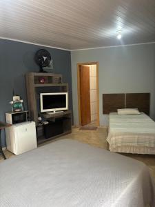 een slaapkamer met een bed en een flatscreen-tv bij Suite/loft Jardim Botanico in Curitiba