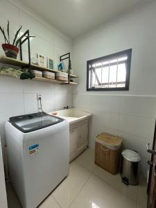 a small white kitchen with a sink and a tub at Casa perto do mar in Capão da Canoa