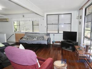 uma sala de estar com um sofá e uma TV em 25 Walkers Point Esplanade em Burrum Heads mais 12 fotografias