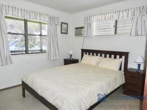 um quarto com uma cama e duas janelas em 25 Walkers Point Esplanade em Burrum Heads