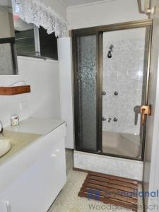 um banheiro com chuveiro e porta de vidro em 25 Walkers Point Esplanade em Burrum Heads