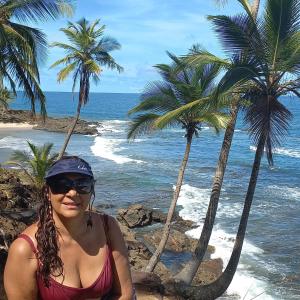 une femme assise sur la plage à côté des palmiers dans l'établissement Apart Lua Cheia 2 quartos caminho das praias, à Itacaré