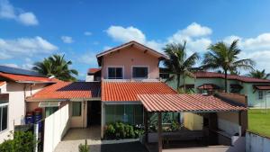 a house with an orange roof and palm trees at Pousada Mar e Luz in Ilha Comprida