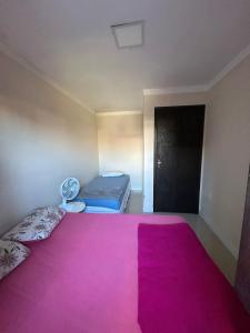 a room with a large pink bed and a black door at Casa perto do mar in Capão da Canoa