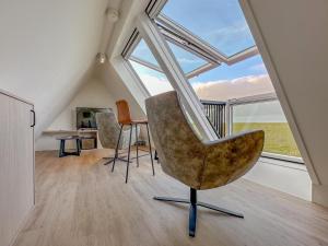 an attic room with a chair and a desk and windows at Happy Beach 48 in Colijnsplaat