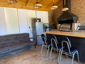 a kitchen with a bar with chairs and a couch at Cabaña con quincho, tinaja y piscina in Coinco