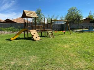 a playground with a slide and a swing set at Cabaña con quincho, tinaja y piscina in Coinco